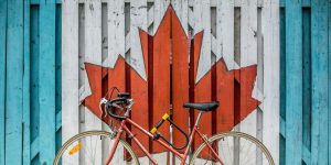 red road bike beside red and white wooden maple leaf painted wall