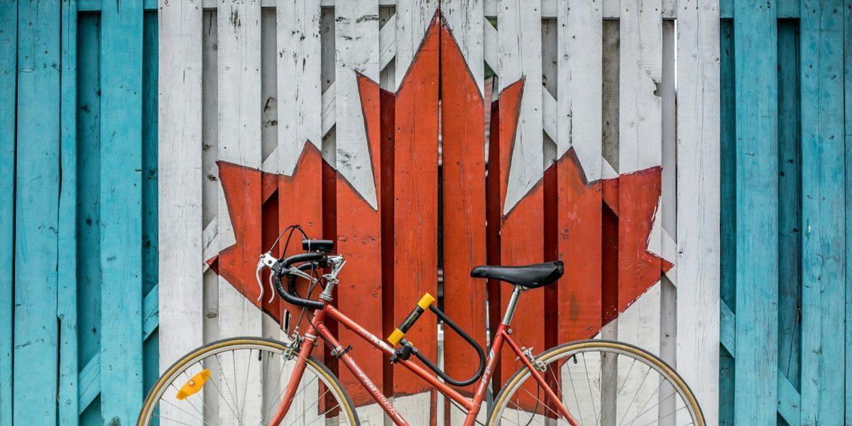 red road bike beside red and white wooden maple leaf painted wall