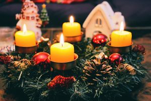 Cozy Christmas display featuring candles, ornaments, and festive wreath in warm candlelight.