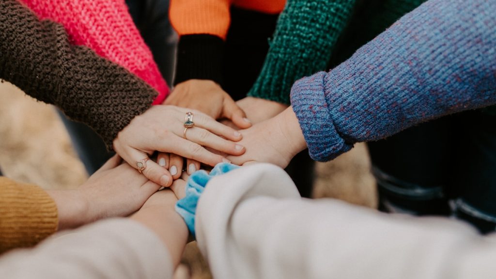 person in red sweater holding babys hand