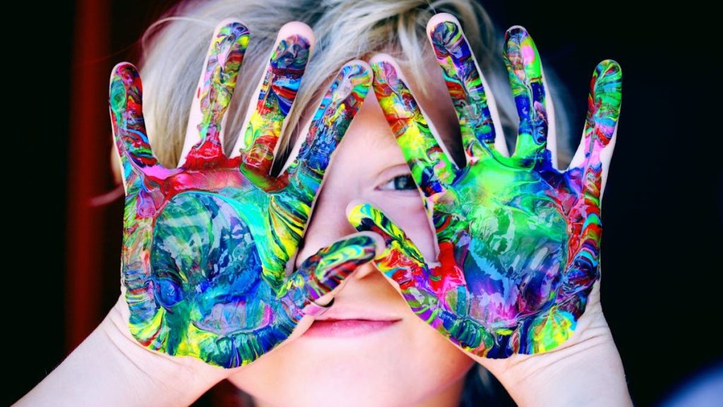 Vibrant close-up of a child's hands covered in colorful paint, expressing creativity and fun.