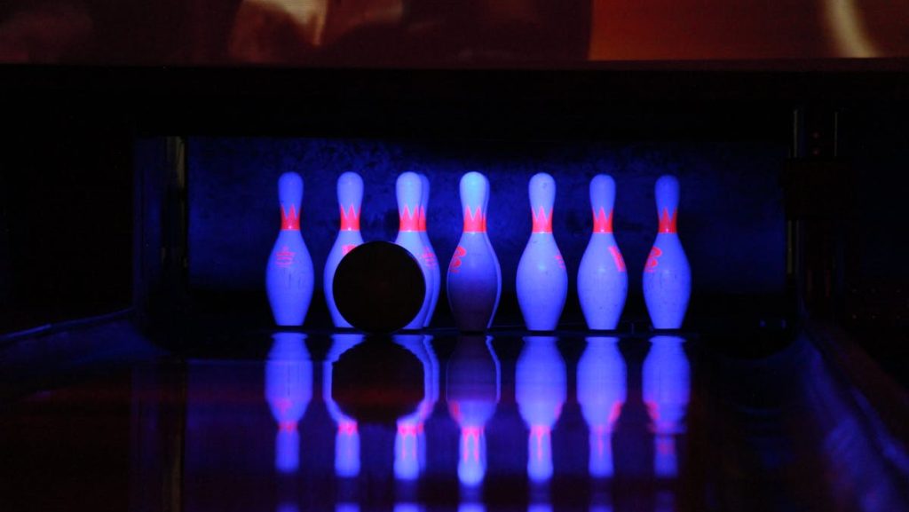 Bowling scene with pins and ball under neon lights, capturing a vibrant nightlife vibe.