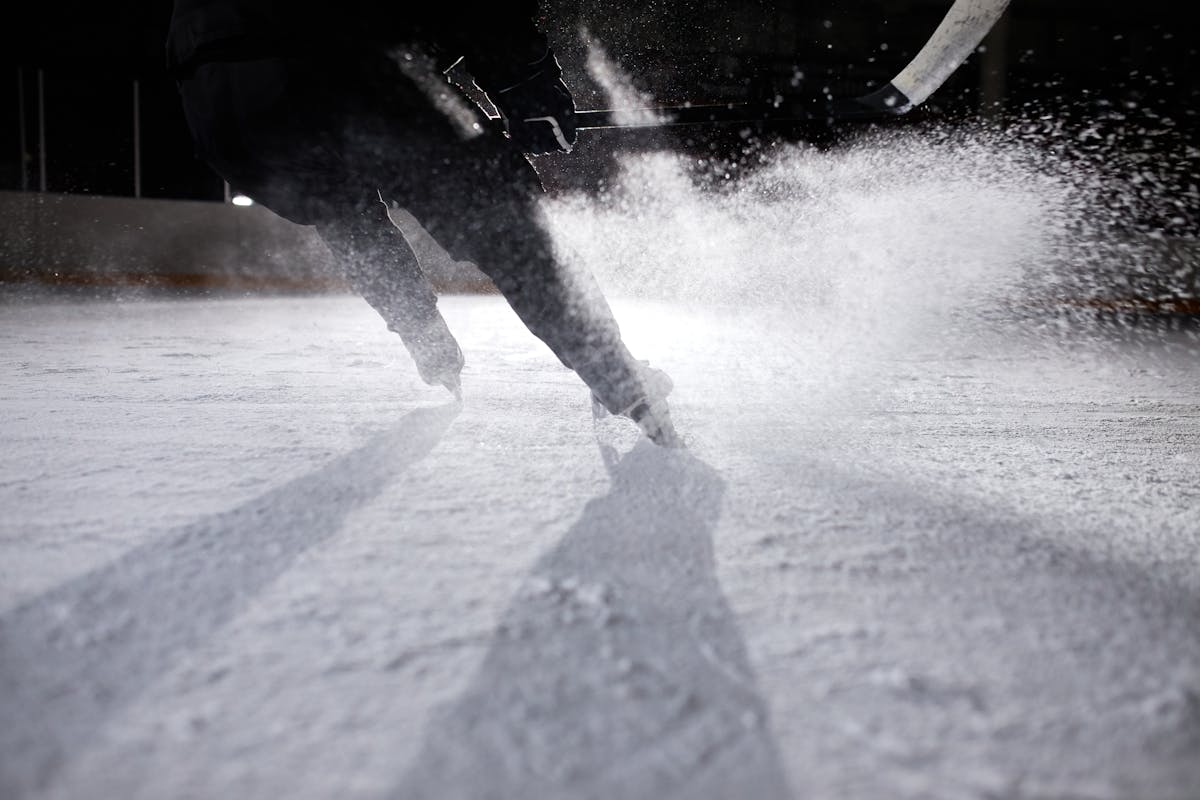 High-energy ice hockey player in action, creating an ice spray during a game on a frozen rink.