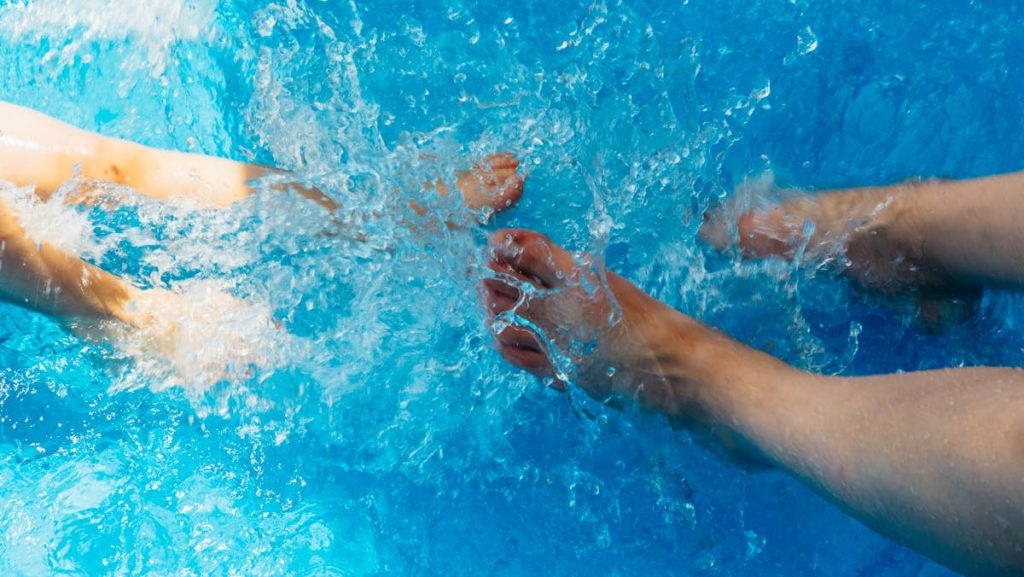 Two people playfully splashing water in a swimming pool. Perfect summer vibes.