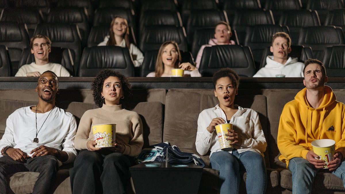 A diverse group of adults watching a movie in a theater, showcasing various expressions and emotions.