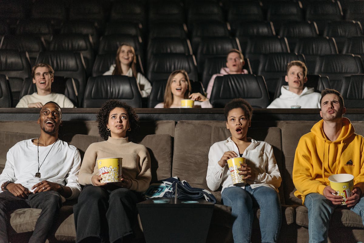 A diverse group of adults watching a movie in a theater, showcasing various expressions and emotions.